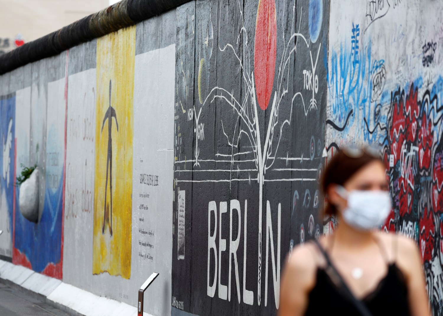 Tourist Ann-Kathrin from Germany wears a face mask as she walks past the East Side Gallery, the largest remaining part of the former Berlin Wall, following the coronavirus (COVID-19) disease outbreak in Berlin, Germany, June 27, 2020.    REUTERS/Fabrizio Bensch