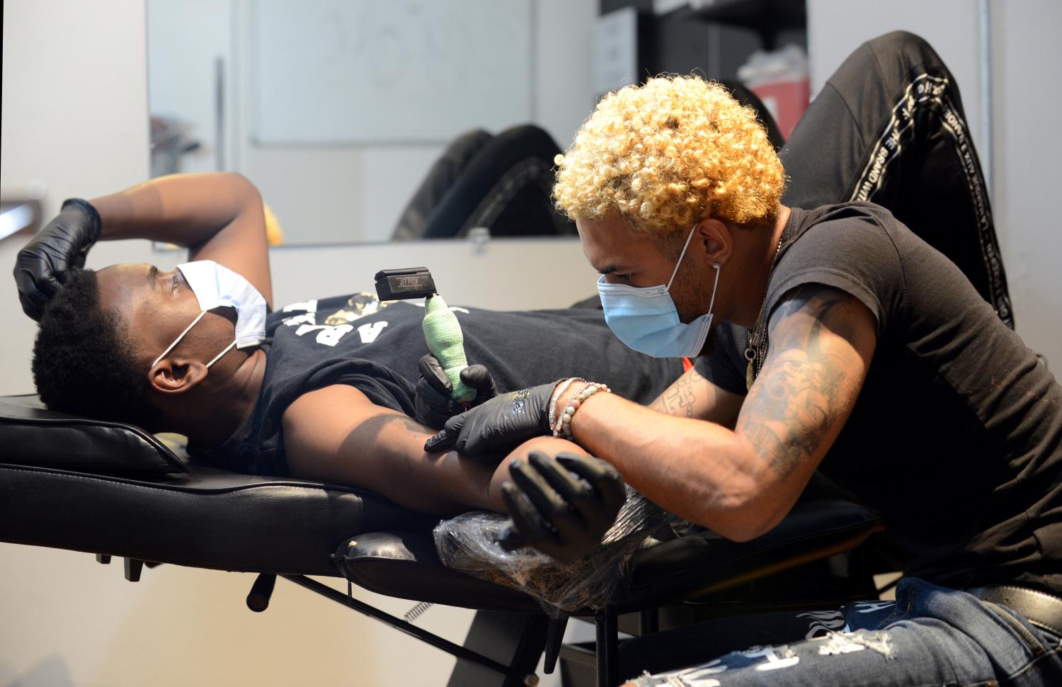 Jay Williams tattoos a customer who gave his name as D OJ at Black Ink Atlanta, during the phased reopening of businesses and restaurants from coronavirus disease (COVID-19) restrictions in the state, in Atlanta, Georgia, U.S., April 24, 2020. REUTERS/Bita Honarvar