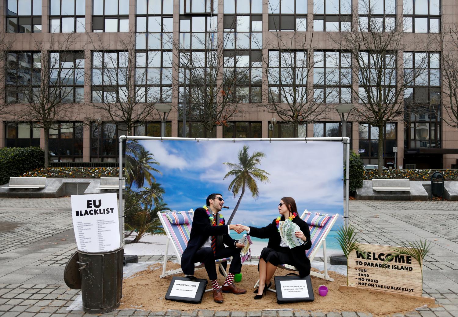 Activists stage a protest on a mock tropical island beach representing a tax haven outside a meeting of European Union finance ministers in Brussels, Belgium, December 5, 2017.  REUTERS/Francois Lenoir