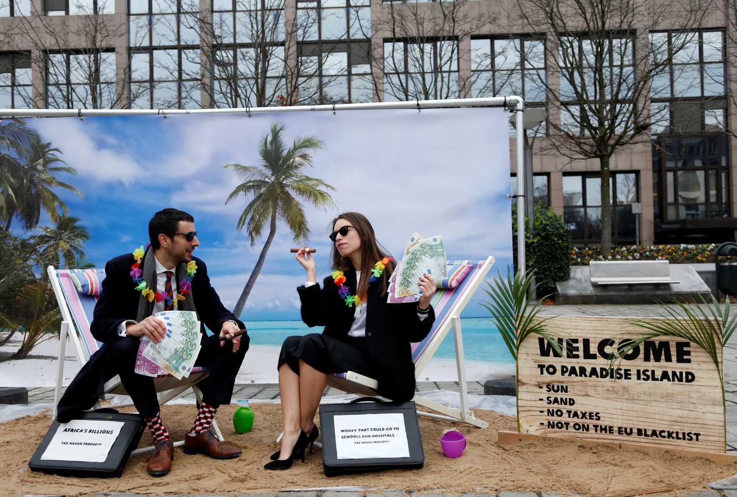 Activists stage a protest on a mock tropical island beach representing a tax haven outside a meeting of European Union finance ministers in Brussels, Belgium, December 5, 2017.  REUTERS/Francois Lenoir