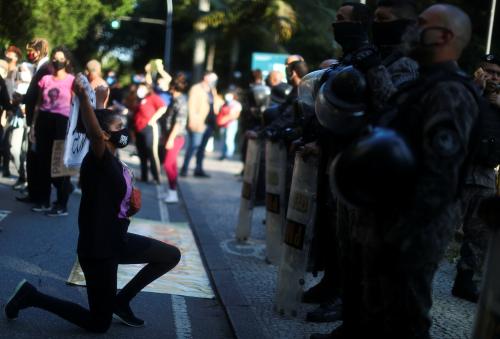 A woman wearing a face mask kneels in front of security forces officers as she takes part in a protest against police violence during operations in slums against drug gangs and racism in Brazil, in front of the Guanabara Palace in Rio de Janeiro, Brazil, May 31, 2020. REUTERS/Pilar Olivares