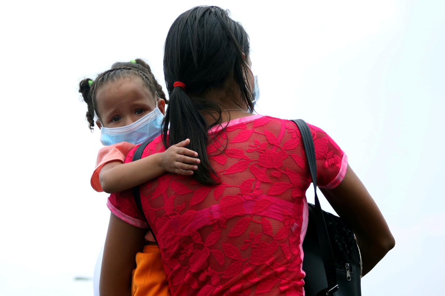 A child wearing protective face mask is carried across the border between Colombia and Venezuela at Simon Bolivar international bridge in Cucuta, Colombia March 12, 2020. REUTERS/Carlos Eduardo Ramirez     TPX IMAGES OF THE DAY