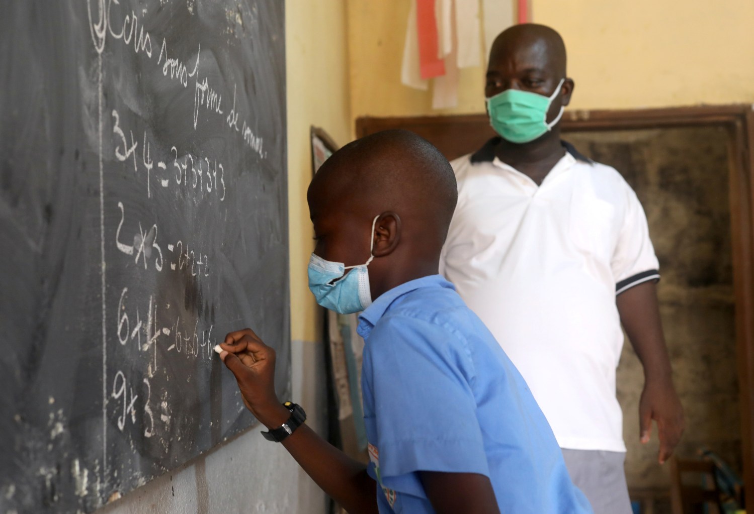 A pupil, wearing a protective mask, writes on a classroom chalkboard at the Merlan school of Paillet during the reopening of schools, as the lockdown due to coronavirus disease (COVID-19) is eased, in Abidjan, Ivory Coast May 25, 2020. REUTERS/Luc Gnago