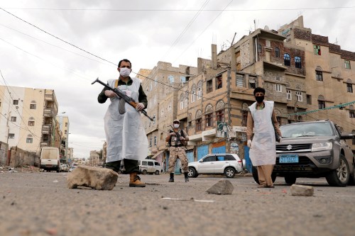 FILE PHOTO: Security men wearing protective masks stand on a street during a 24-hour curfew amid concerns about the spread of the coronavirus disease (COVID-19), in Sanaa, Yemen May 6, 2020. REUTERS/Khaled Abdullah/File Photo