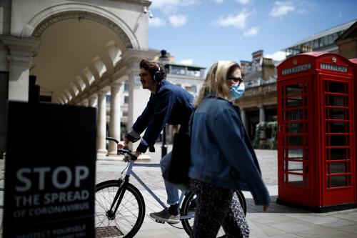 A woman walks as a man rides a bike, amid the coronavirus disease (COVID-19) outbreak, in Covent Garden, in London, Britain, June 29, 2020. REUTERS/Henry Nicholls