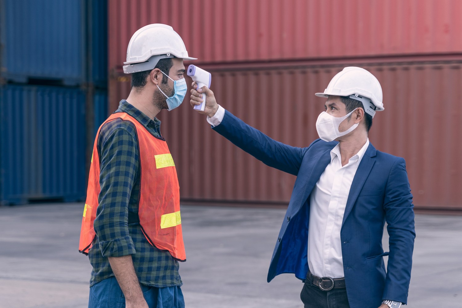Worker with mask getting temperature taken