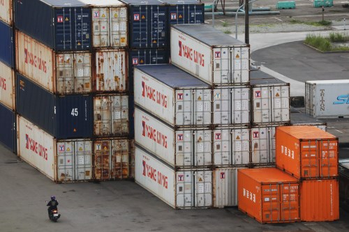 A person drives a motorcycle by shipping containers at a port in Keelung, Taiwan, June 10, 2020. REUTERS/Ann Wang