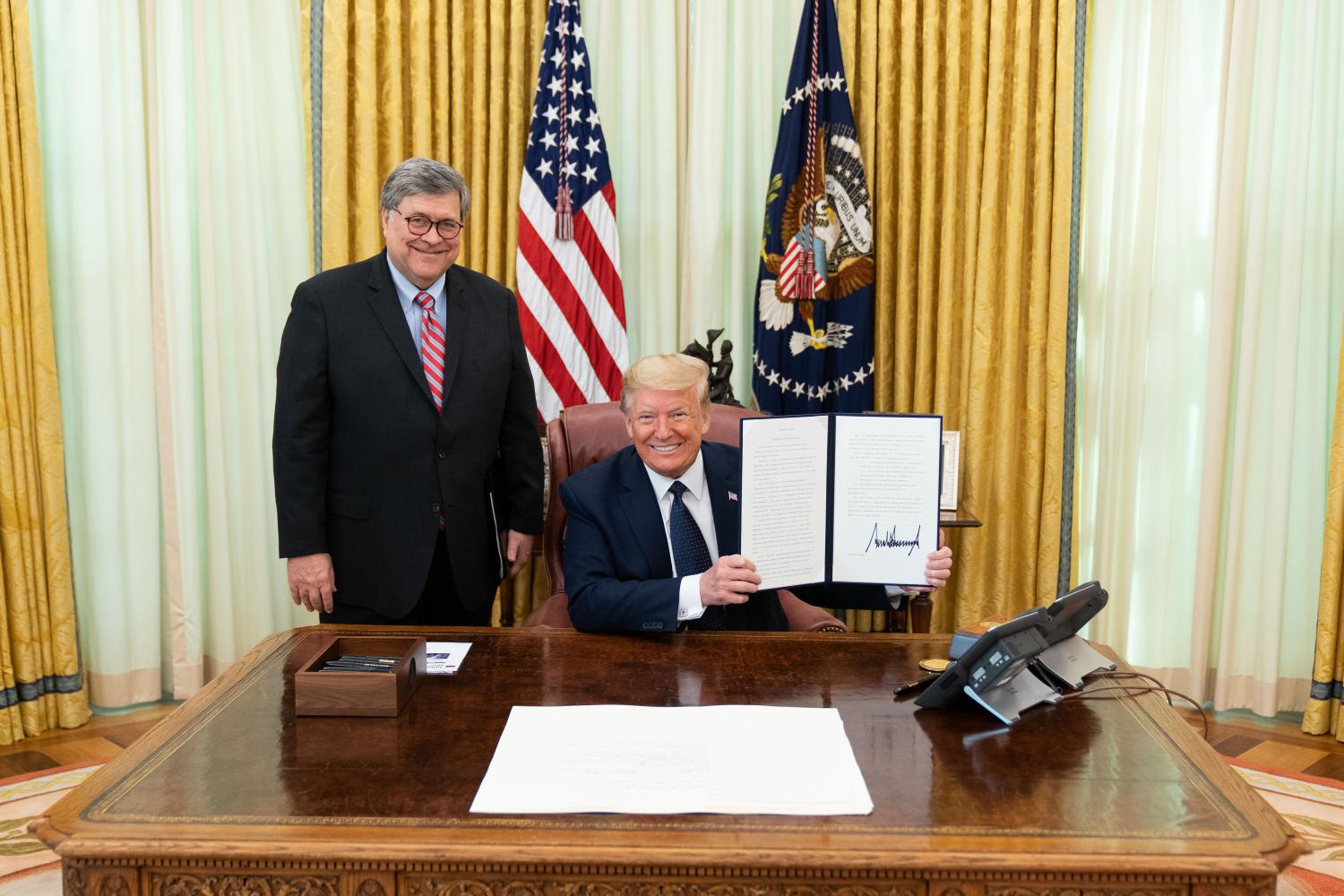 WASHINGTON, UNITED STATES - President Donald J. Trump (right) signs an executive order on preventing online censorship in the Oval Office of the White House in Washington, United States on May 28, 2020. Trump signed an executive order that directs federal agencies to clarify the scope of a US law known as Section 230, which protects Internet companies from liability for content posted by users and allows them to regulate or delete posts that, while legal, are objectionable.