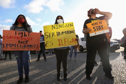 People hold signs as they take part in a rally for "Justice Everywhere" to celebrate the U.S. Supreme Court's ruling to disallow the rescinding of the Deferred Action for Childhood Arrivals (DACA) program, in San Diego, California, U.S., June 18, 2020. The sign in the middle reads: "No human being is illegal". REUTERS/Mike Blake