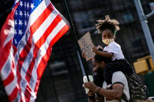 A child looks on with a sign while her father carries a U.S. flag during a protest against racial inequality in the aftermath of the death in Minneapolis police custody of George Floyd, in front of the at Grand Army Plaza in the Brooklyn borough of New York City, New York, U.S. June 7, 2020. REUTERS/Eduardo Munoz
