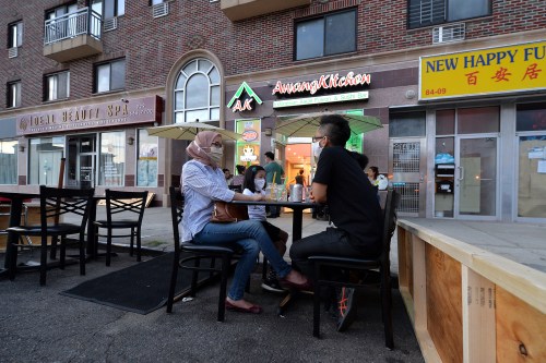 Wearing masks in the time of COVID-19, the Sukarmadijaya family sit dine al fresco at a table set up off the sidewalk in front of Awang Kitchen, an Indonesian restaurant along Queens Boulevard, in the Elmhurst section of Queens, NY, June 26, 2020. Under Phase II, restaurants may serve customers at sidewalk tables and 8ft into the street from sidewalk, all meant to prevent the further spread of COVID-19 pandemic. (Anthony Behar/Sipa USA)No Use UK. No Use Germany.