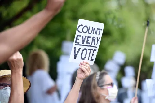 A person holding up a sign that says "Count every vote."
