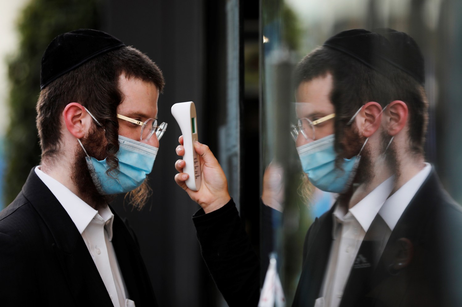 A visitor gets his temperature measured as he wears a face mask at a fashion shopping center in Ashdod, as restrictions over the coronavirus disease (COVID-19) ease around Israel, May 5, 2020. REUTERS/Amir Cohen