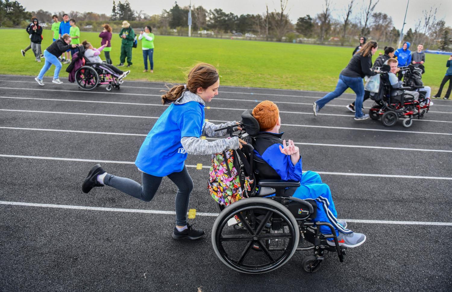 Competitors in wheelchairs get some assistance around the track during the Developmental Adapted Physical Education track meet Friday, May 10, at Apollo High School. Students from St. Cloud junior and high schools, Sartell, Sauk Rapids and Foley students took part in the area event, the first of its kind at Apollo.Poy 27