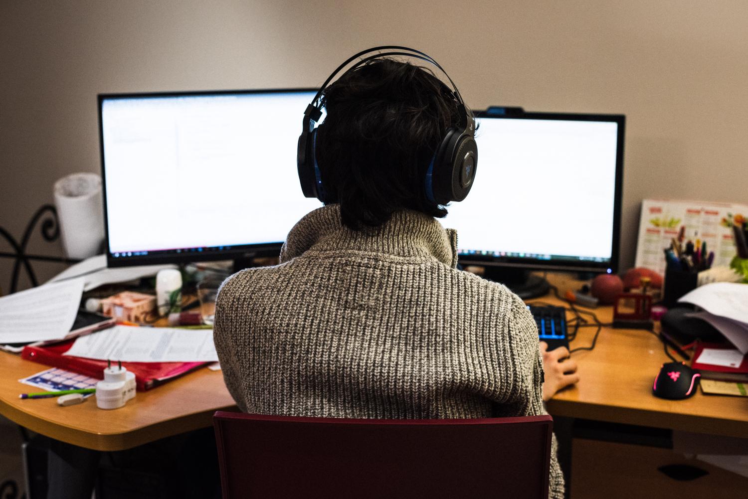 A third-grade schoolboy seen from behind has headphones on his head. He is taking online courses from his home in Toulouse on the first day of the containment measures imposed by the government. He has a double screen in front of him.Un collegien vu de dos a un casque audio sur le tete. Il suit des cours en ligne depuis son domicile a Toulouse le premier jour des mesures de confinement imposees par le gouvernement en France. Il a un double ecran devant lui.NO USE FRANCE