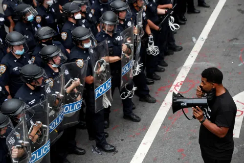 A demonstrator stands in front of New York Police Department (NYPD) officers inside of an area being called the "City Hall Autonomous Zone" that has been established to protest the New York Police Department and in support of "Black Lives Matter" near City Hall in lower Manhattan, in New York City, U.S., July 1, 2020. REUTERS/Andrew Kelly     TPX IMAGES OF THE DAY