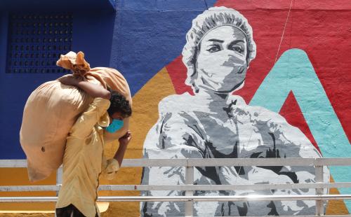 A man carrying a sack walks past a graffiti of a healthcare worker during a lockdown to slow the spread of the coronavirus disease (COVID-19) in Mumbai, India June 29, 2020. REUTERS/Francis Mascarenhas