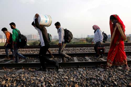 Migrant workers with their faces covered and carrying their belongings, walk along a railway track to return to their home state of eastern Bihar, during an extended nationwide lockdown to slow the spread of the coronavirus disease (COVID-19), in Ghaziabad, in the outskirts of New Delhi, India, May 13, 2020. REUTERS/Adnan Abidi
