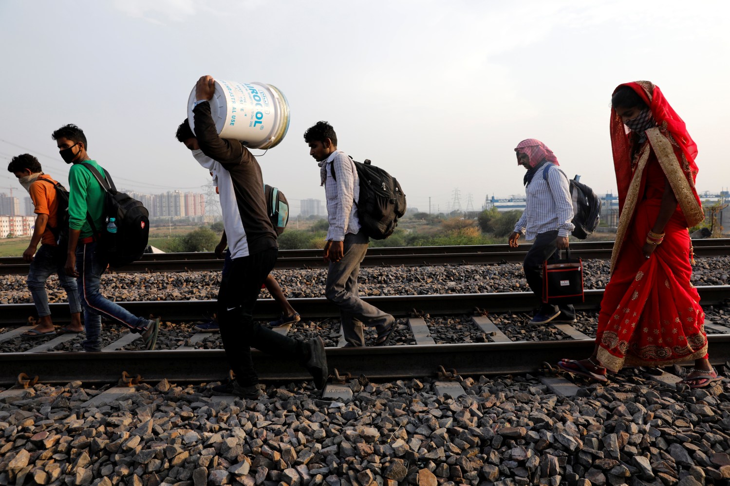Migrant workers with their faces covered and carrying their belongings, walk along a railway track to return to their home state of eastern Bihar, during an extended nationwide lockdown to slow the spread of the coronavirus disease (COVID-19), in Ghaziabad, in the outskirts of New Delhi, India, May 13, 2020. REUTERS/Adnan Abidi