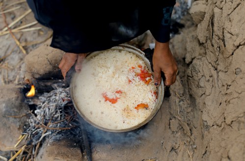Sister of ten-year-old malnourished girl Afaf Hussein holds a pot of rice she cooked in their kitchen outside their house in the village of al-Jaraib in the northwestern province of Hajjah, Yemen, February 19, 2019. REUTERS/Khaled Abdullah
