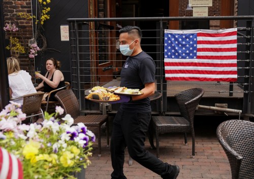 As Phase One of reopening begins in Northern Virginia today, a waiter in a face mask to protect against the coronavirus (COVID-19) serves diners seated outdoors at a restaurant in Alexandria, Virginia, U.S., May 29, 2020.  REUTERS/Kevin Lamarque