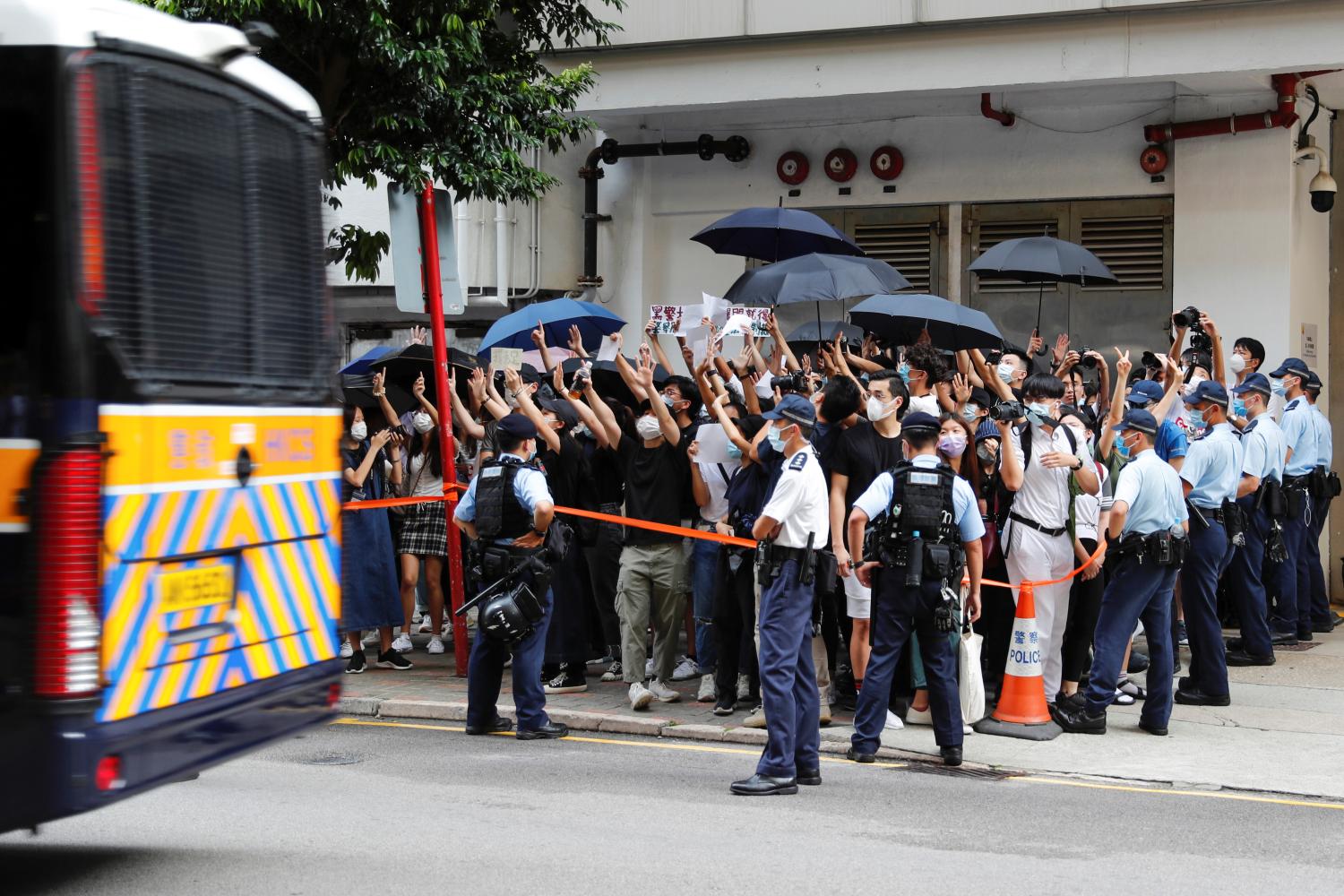 Supporters raise white paper to avoid slogans banned under the national security law as they support arrested anti-law protester, as a prison van leaves Eastern court in Hong Kong, China July 3, 2020. REUTERS/Tyrone Siu