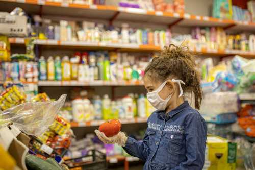 Little girl picking fresh tomatoes in the grocery store