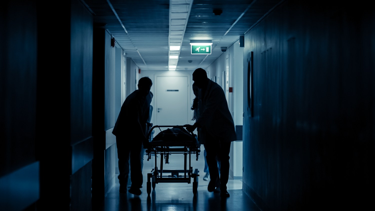 Hospital staff push a gurney through a hospital corridor