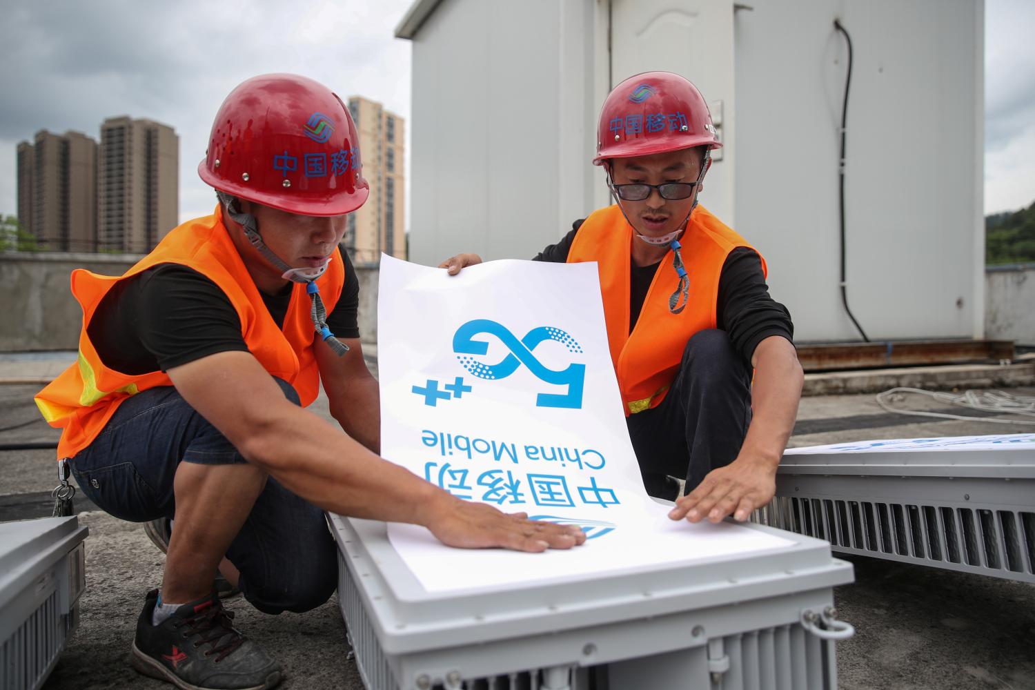 Workers place a China Mobile 5G sign on an equipment as they set up a 5G network base station in Fenggang, Guizhou province, China May 26, 2020. Picture taken May 26, 2020. cnsphoto via REUTERS   ATTENTION EDITORS - THIS IMAGE WAS PROVIDED BY A THIRD PARTY. CHINA OUT.