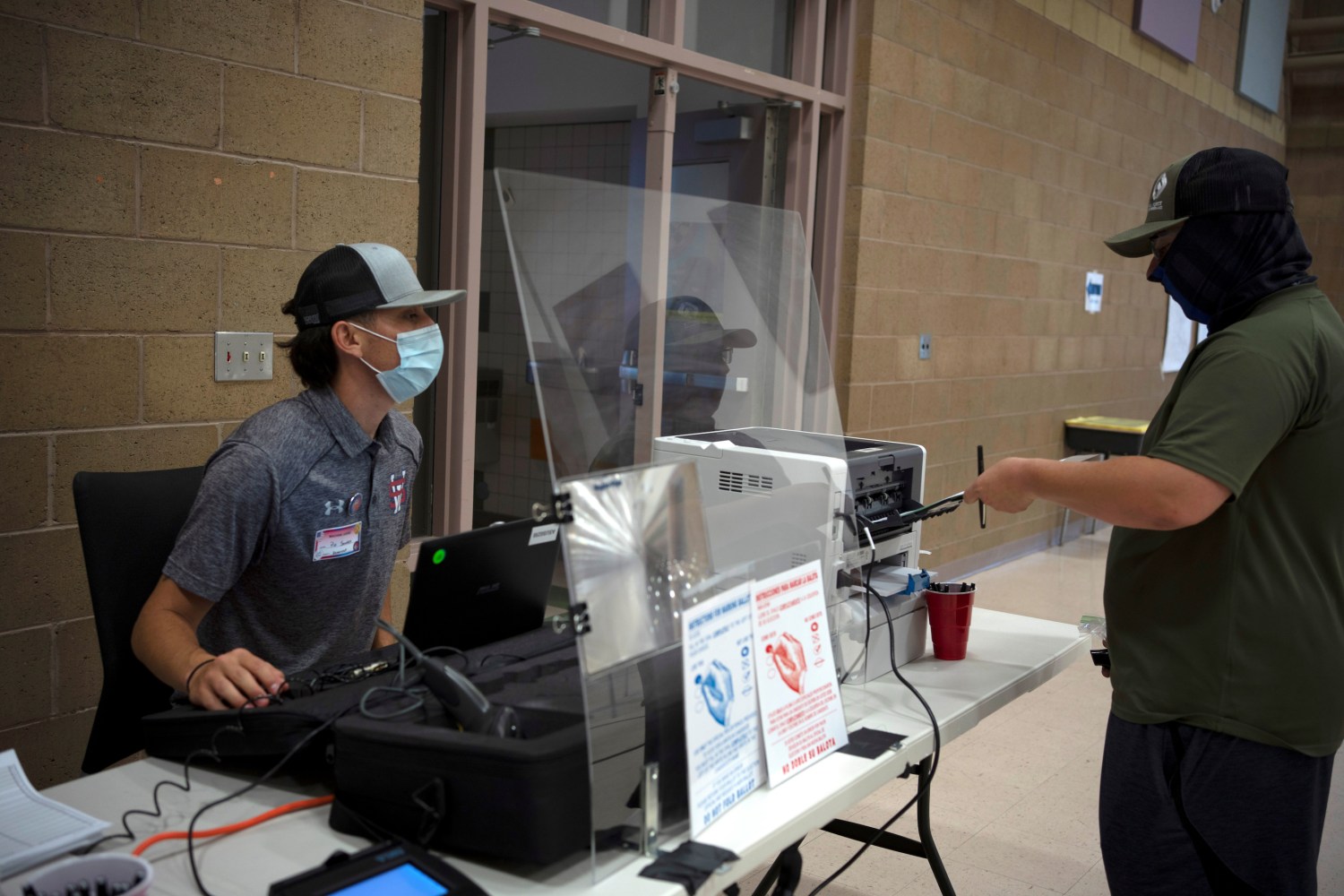 Caleb Kirkland, (R) gets his ballot from machine judge Pio Sancez during the primary election at Sonoma Elementary School in Las Cruces, New Mexico, U.S., June 2, 2020. REUTERS/Paul Ratje