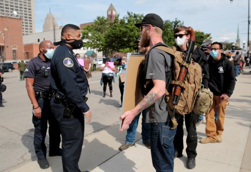 A Detroit Police officer talks with two armed men, one of whom is carrying a "The Boogaloo stands with George Floyd" sign, during a rally against the death in Minneapolis police custody of George Floyd, in Detroit, Michigan, U.S. May 30, 2020.  Picture taken May 30, 2020.   REUTERS/Rebecca Cook