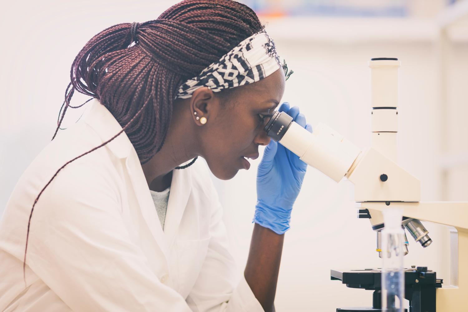 Young female scientist looking through a microscope in the laboratory
