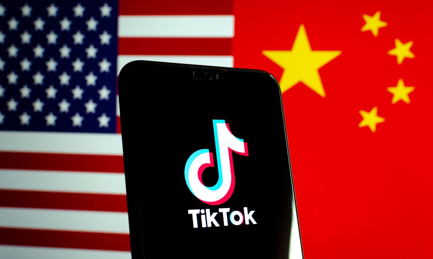 Phone with TikTok app open, over U.S. and Chinese flags