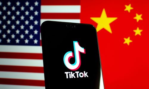 Phone with TikTok app open, over U.S. and Chinese flags