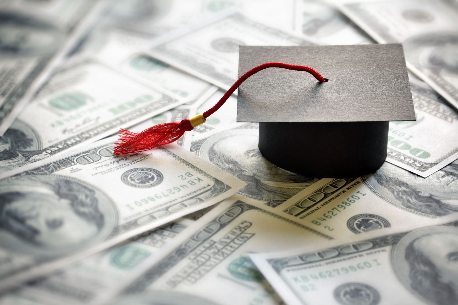 Graduation cap on $100 bills, representing student debt