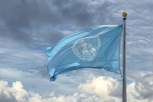 Flag of the United Nations flying in a cloudy blue sky
