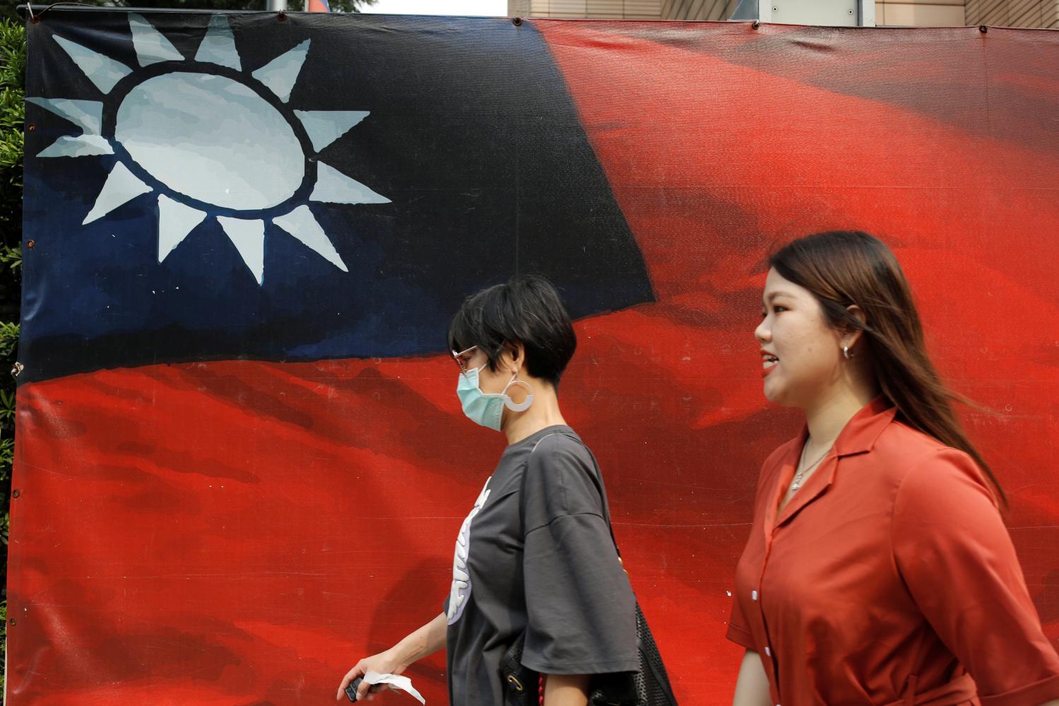 People walk past a Taiwanese flag amid the coronavirus disease (COVID-19) pandemic in Taipei, Taiwan, August 10, 2020. REUTERS/Ann Wang