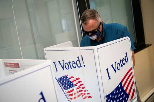 A man wears a face mask featuring the seal of Virginia as he fills out his ballot at an early voting site in Arlington, Virginia, U.S., September 18, 2020. REUTERS/Al Drago