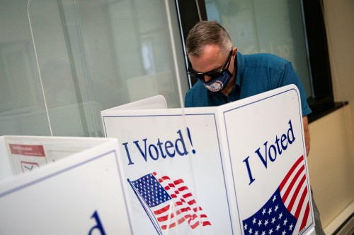 A man wears a face mask featuring the seal of Virginia as he fills out his ballot at an early voting site in Arlington, Virginia, U.S., September 18, 2020. REUTERS/Al Drago