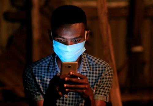 A soccer fan uses his mobile phone for betting during a television broadcast at a soccer theatre called the San Siro Stadium as the English Premier League season resumes after a three-month stoppage due to the coronavirus disease (COVID-19) spread, in Kibera district of Nairobi, Kenya June 17, 2020. REUTERS/Thomas Mukoya