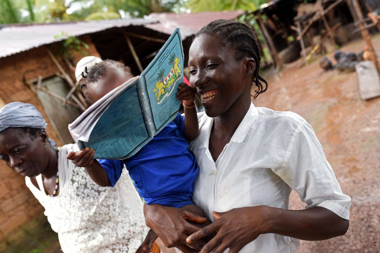 Mariatu Sesay, 15, smiles as she carries her daughter Nadia while she walks outside her house in the countryside village of Sierra Leone  July 11, 2019. REUTERS/Cooper Inveen