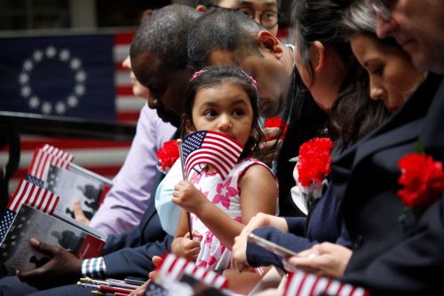 Philadelphia, PA / USA - June 14, 2019: The daughter of a immigrant holds an American flag while she joins her mother's naturalization ceremony on Flag Day at the historic Betsy Ross House. Jana Shea / Shutterstock.com
