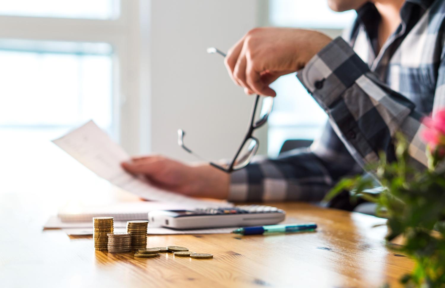 Man looking at a letter on a table with a calculator and money