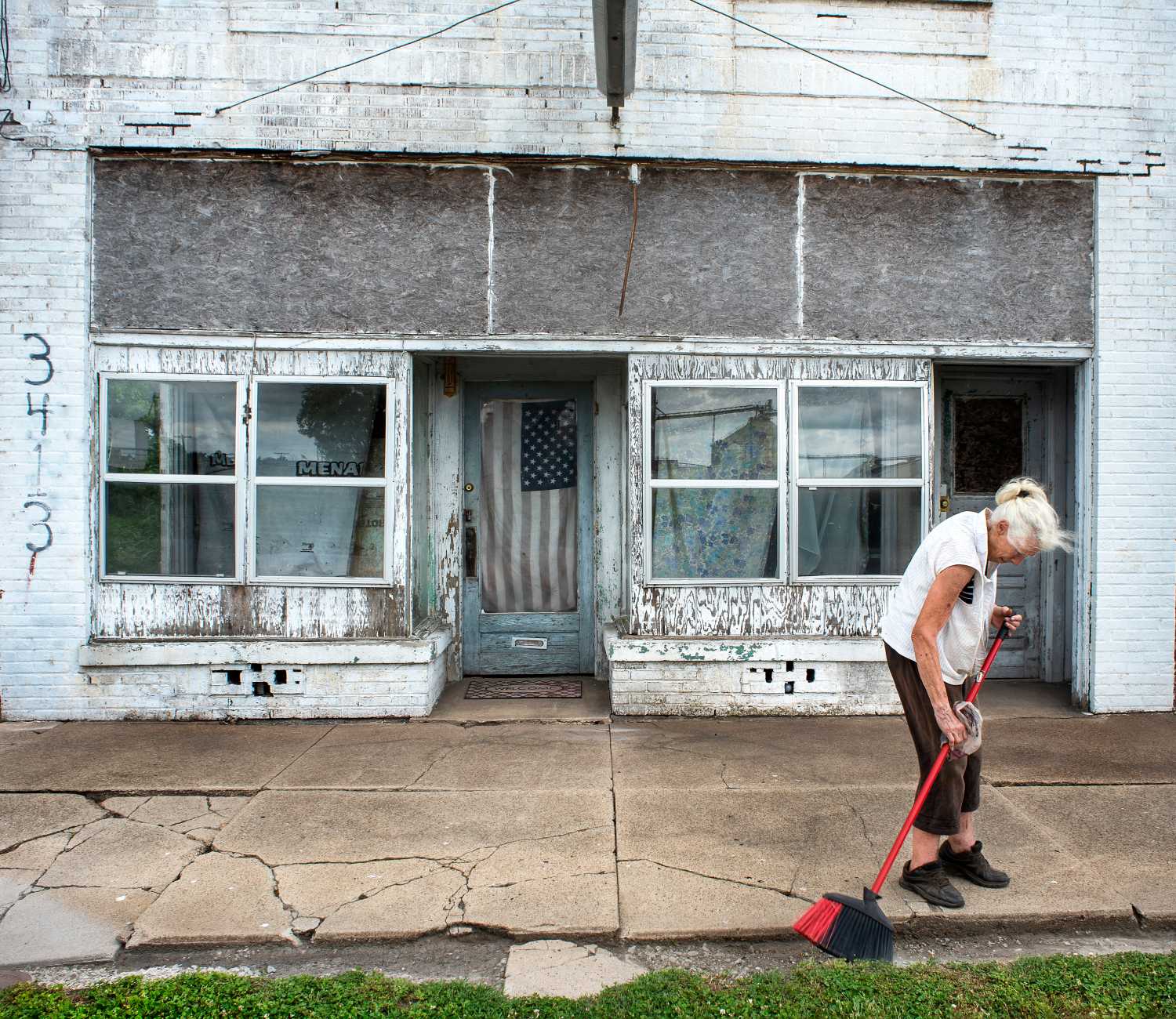 Woman sweets street in front of closed business.