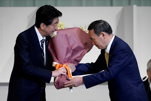 Japan's Chief Cabinet Secretary Yoshihide Suga presents Prime Minister Shinzo Abe with flowers after Suga was elected as new head of the ruling party at the Liberal Democratic Party's (LDP) leadership election in Tokyo, Japan September 14, 2020. Eugene Hoshiko/Pool via REUTERS REFILE - CORRECTING FLOWERS RECIPIENT
