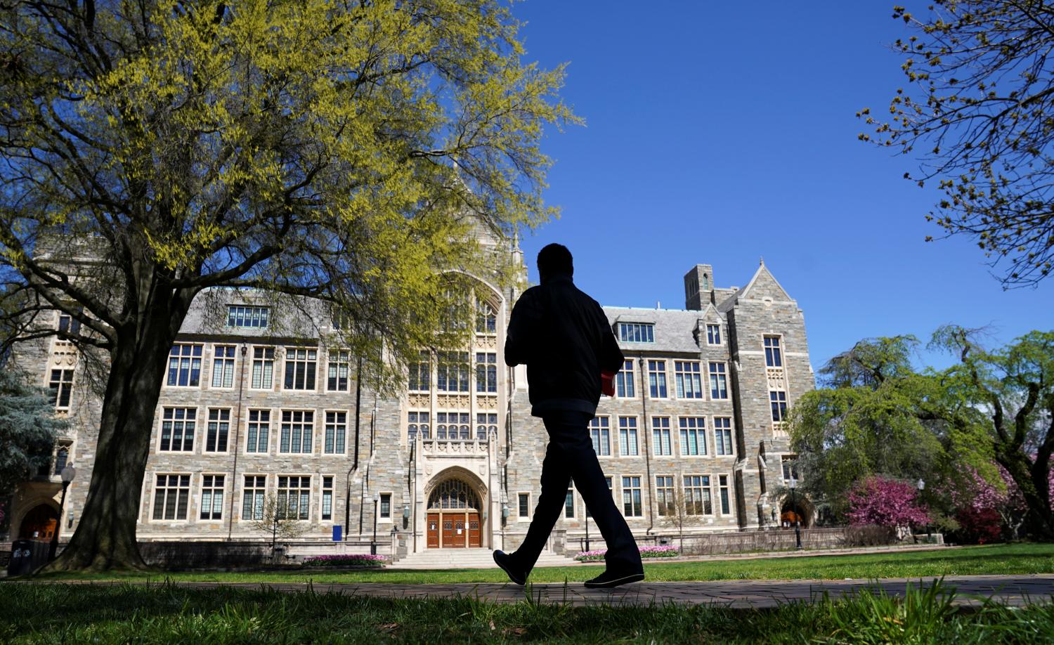 A man walks at an empty campus green at Georgetown University, closed weeks ago due to coronavirus, in Washington, U.S., April 3, 2020. REUTERS/Kevin Lamarque