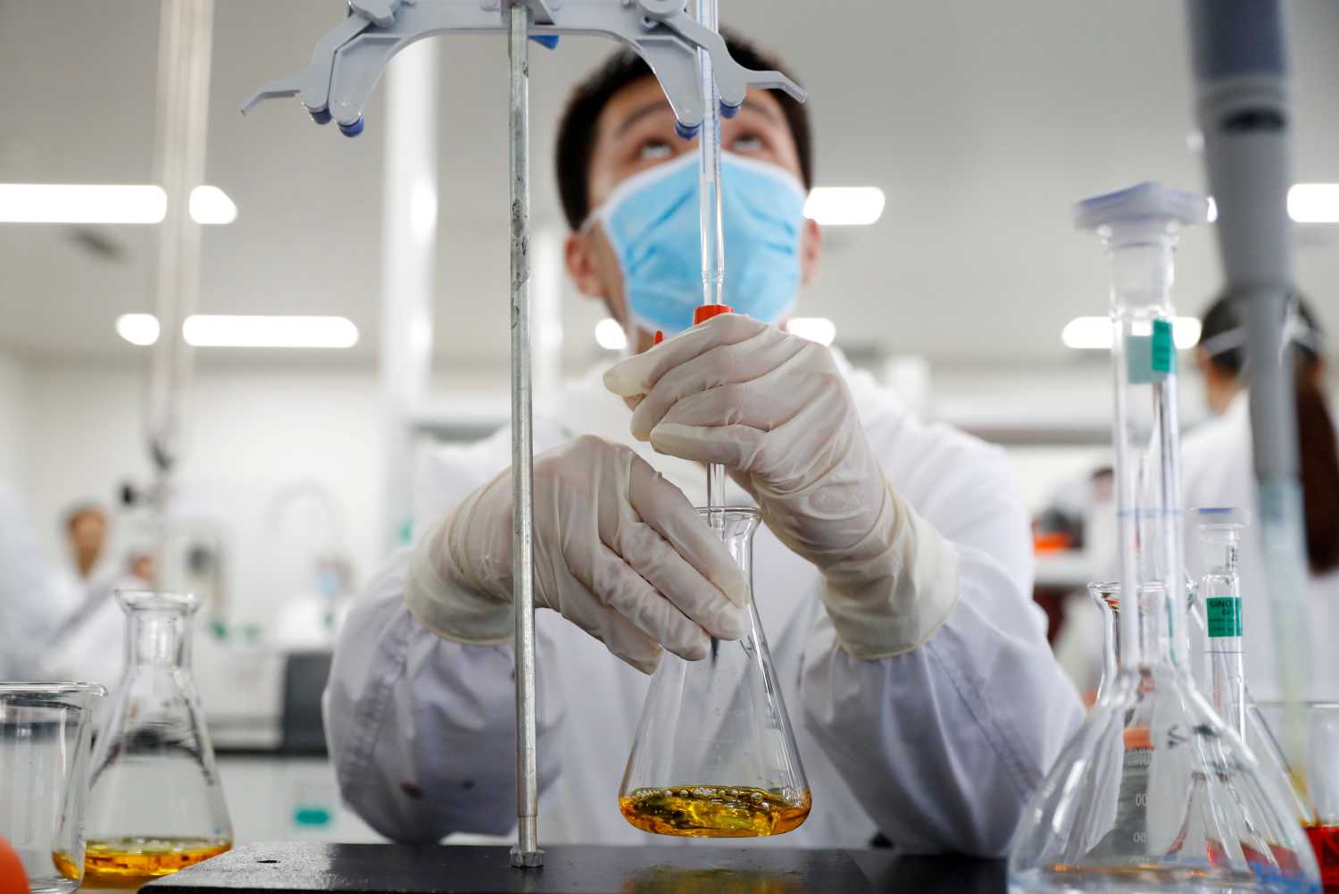 A man wearing gloves and a mask works in a Chinese lab developing an experimental COVID-19 vaccine.