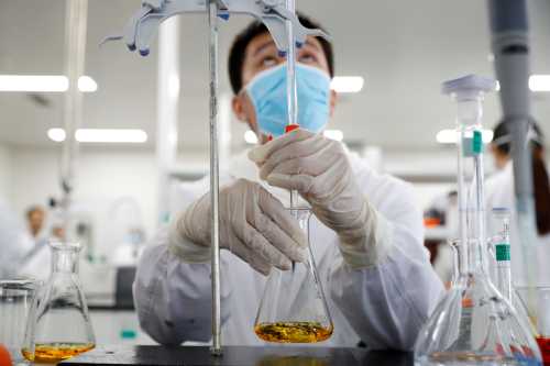 A man wearing gloves and a mask works in a Chinese lab developing an experimental COVID-19 vaccine.