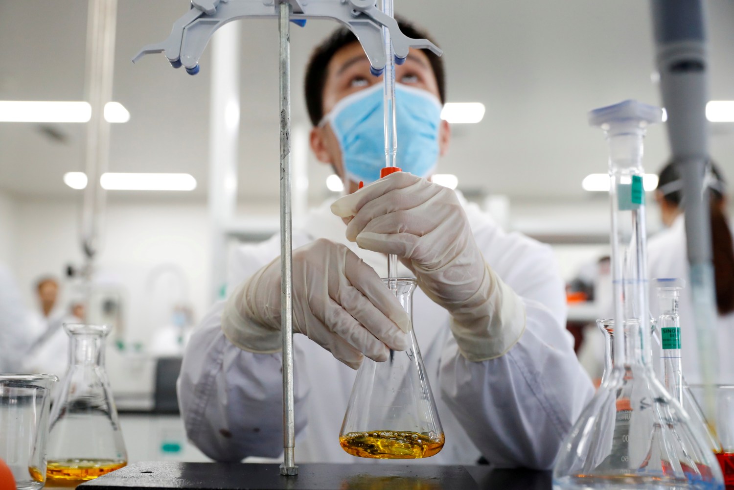 A man wearing gloves and a mask works in a Chinese lab developing an experimental COVID-19 vaccine.