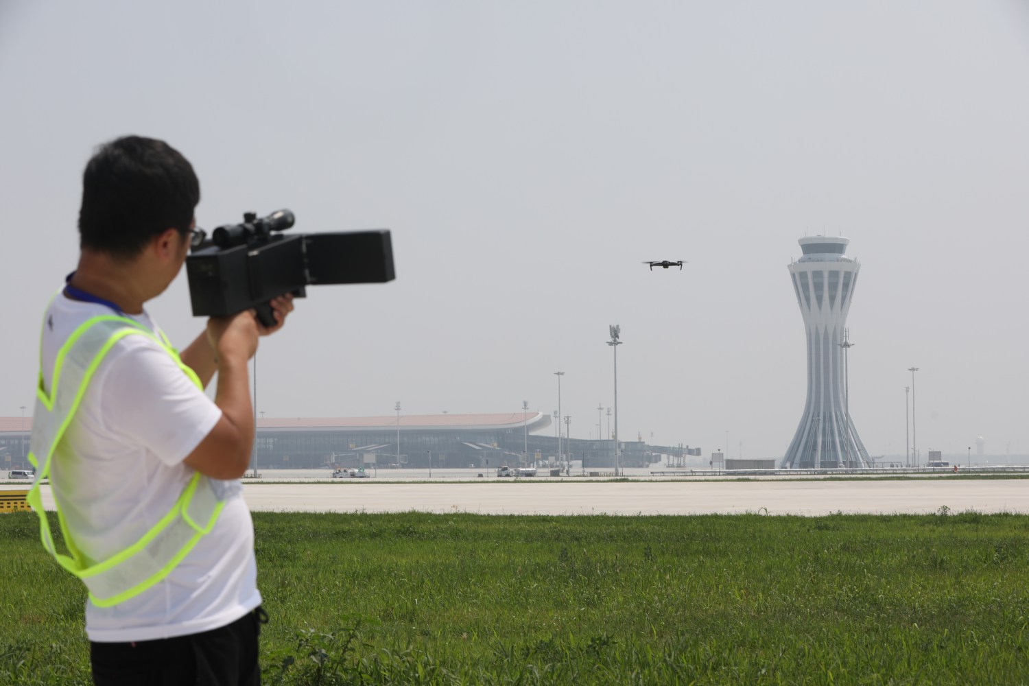 A man in a high-visibility vest tests an anti-drone system at Beijing's international airport.
